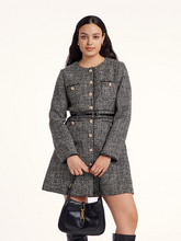 a curvy lady in black tweed dress holding a handbag